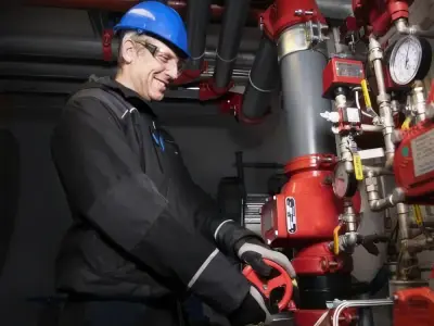 Smilende servicetekniker ved sprinkleranlegg